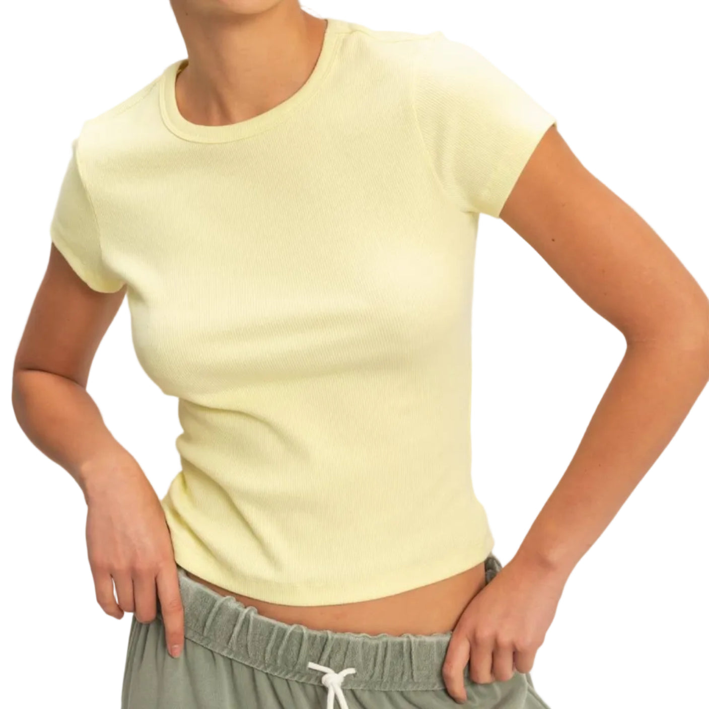 Woman wearing a light yellow t-shirt and green pants against a plain background