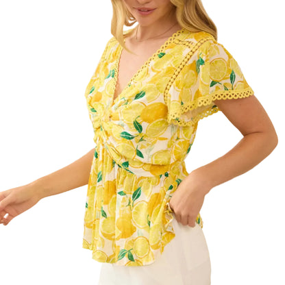 Woman wearing a yellow lemon print top in a bright room