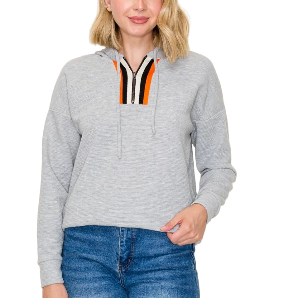 Woman wearing a gray hoodie with a colorful zipper pull against a white background