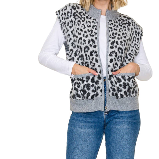 Woman wearing a leopard print vest over a white shirt and blue jeans on a beige background