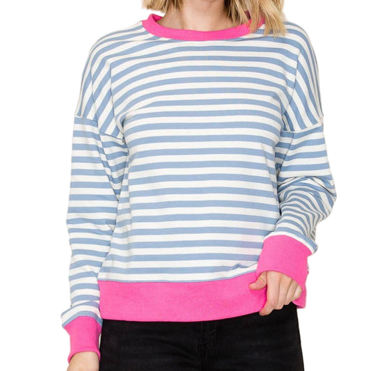 Woman wearing a striped sweater with pink trim on a plain background