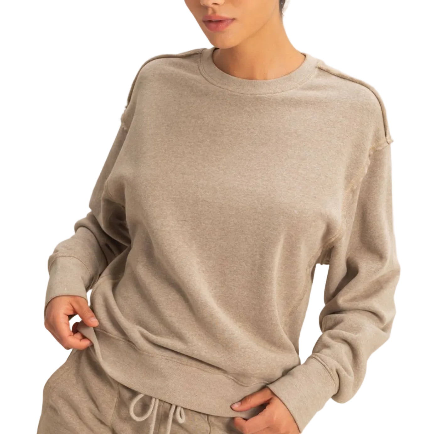 Woman wearing a beige sweater and pants set against a plain background