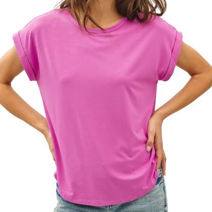 Woman wearing a bright pink t-shirt and blue jeans against a plain background