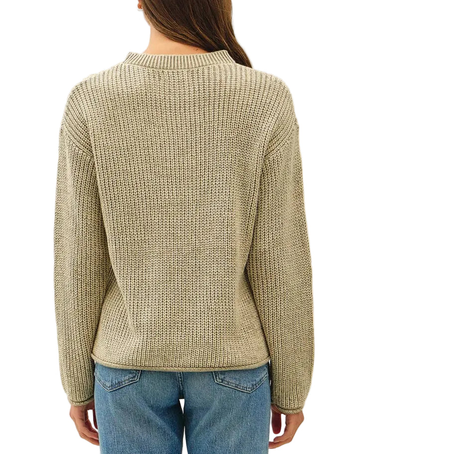 A woman viewed from behind wearing a beige ribbed knit sweater, blue jeans, and brown sandals against a plain white studio background.