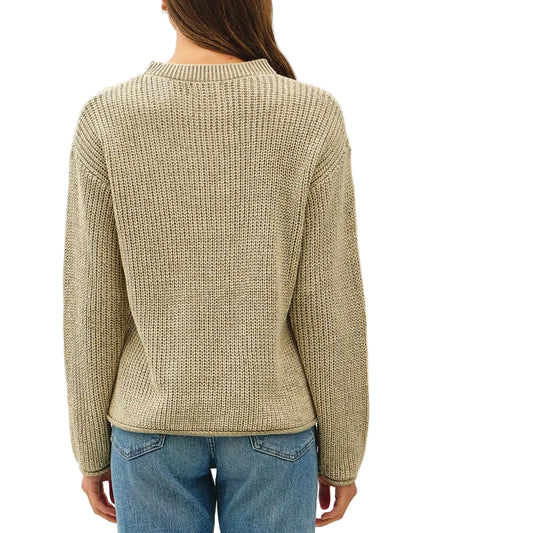 A woman viewed from behind wearing a beige ribbed knit sweater, blue jeans, and brown sandals against a plain white studio background.