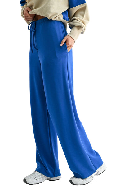 Person wearing blue pants and a beige top on a white background