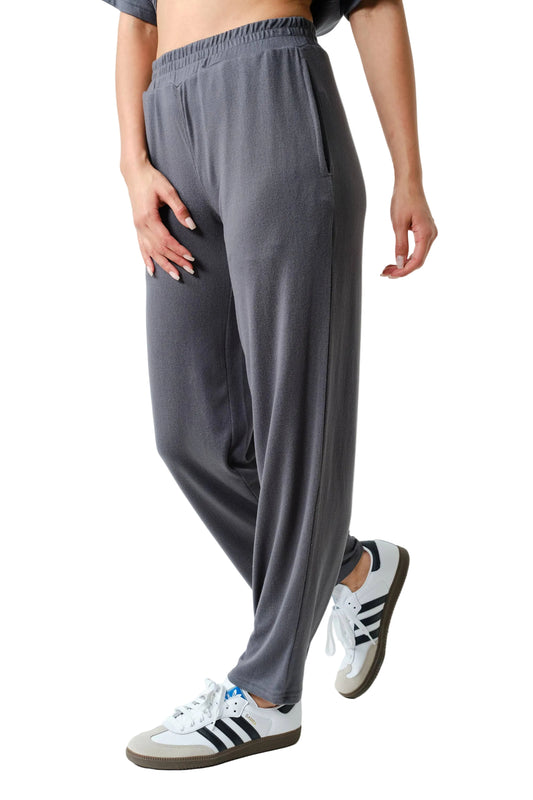 Person wearing gray sweatpants and white sneakers with black stripes on a light background