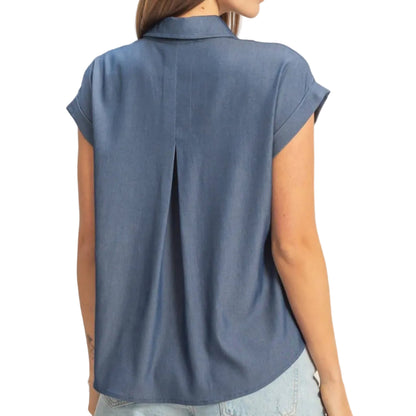 Woman wearing a blue sleeveless shirt and denim shorts on a beige background