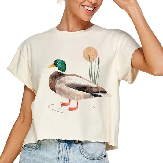 Woman wearing a t-shirt with a duck graphic and denim shorts on a plain background