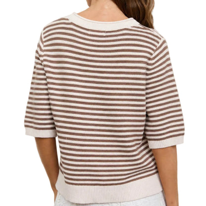 Woman wearing a striped shirt standing in front of a neutral background