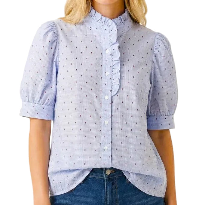 Woman wearing a light blue polka dot blouse and denim shorts on a white background