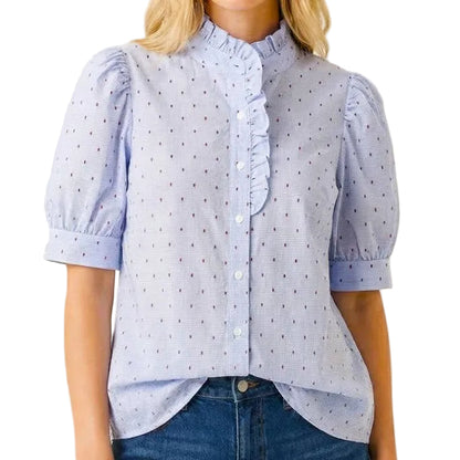 Woman wearing a light blue polka dot blouse and denim shorts on a white background