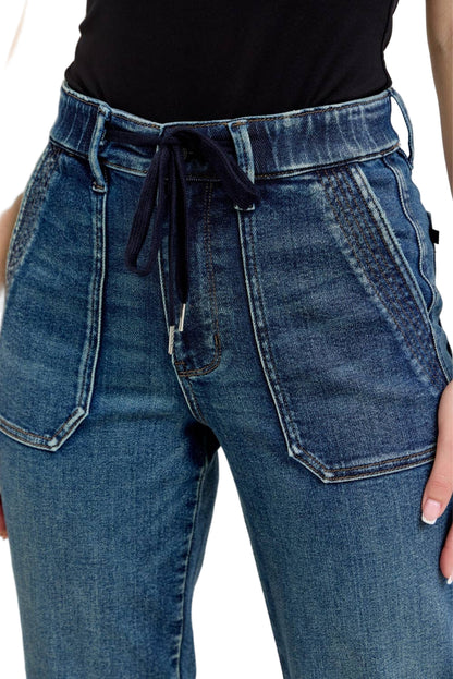 Close-up of blue jeans with a black top worn by a person on a neutral background