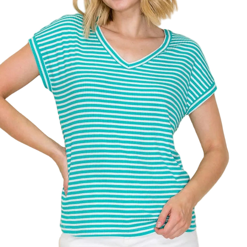 Woman wearing a teal and white striped shirt with white shorts on a beige background