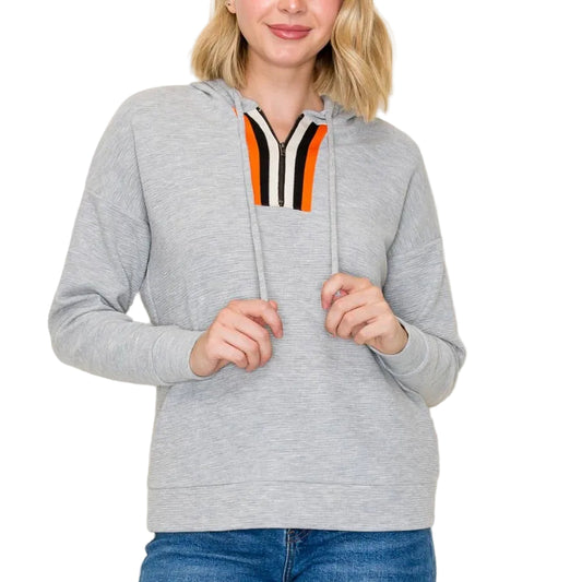 Woman wearing a gray hoodie with a colorful stripe on a plain background
