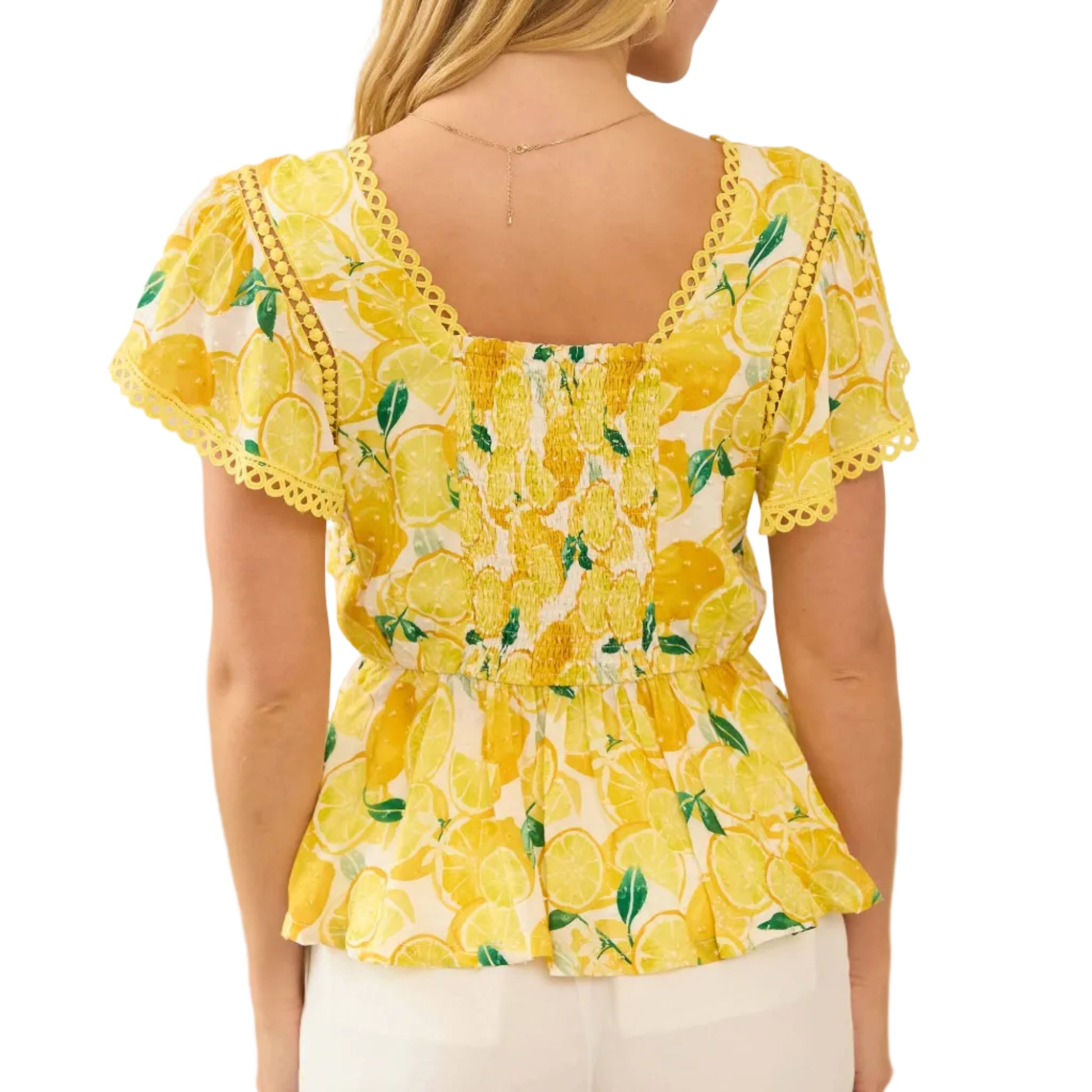 Woman wearing a yellow floral blouse with ruffled sleeves in a neutral setting