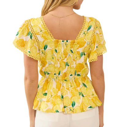 Woman wearing a yellow floral blouse with ruffled sleeves in a neutral setting