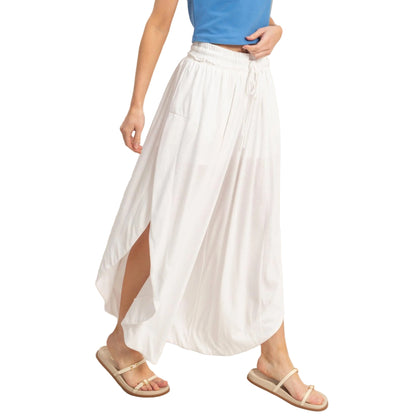 Person wearing a white skirt and blue top on a plain background