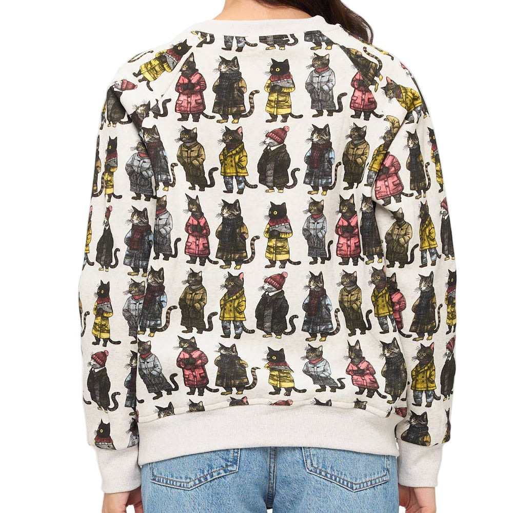 Person wearing a sweater with a cat pattern on a plain background