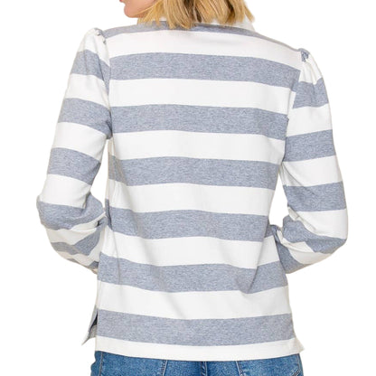 Woman wearing a gray and white striped sweater with blue jeans on a beige background