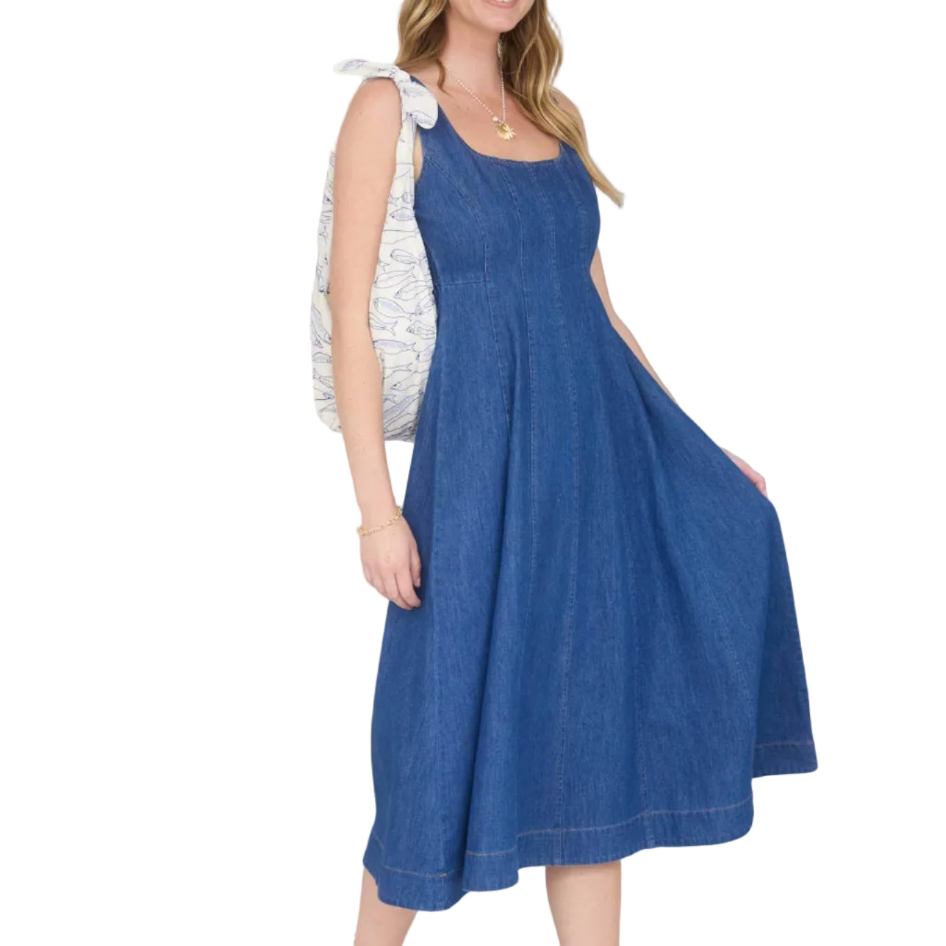 Woman in a blue dress and cap standing in a room with striped curtains and a YETI cooler.