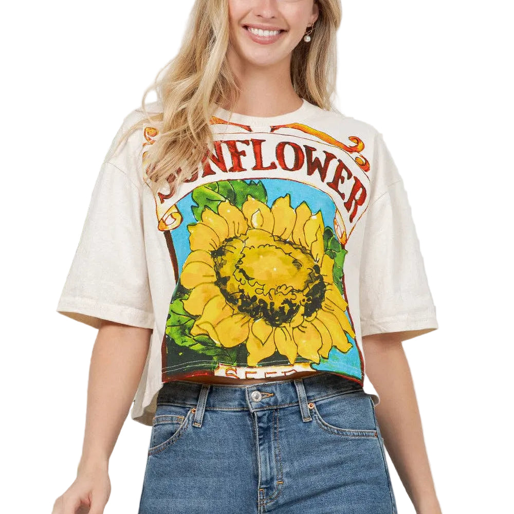 Woman wearing a graphic t-shirt with a sunflower design and text, standing against a light background.
