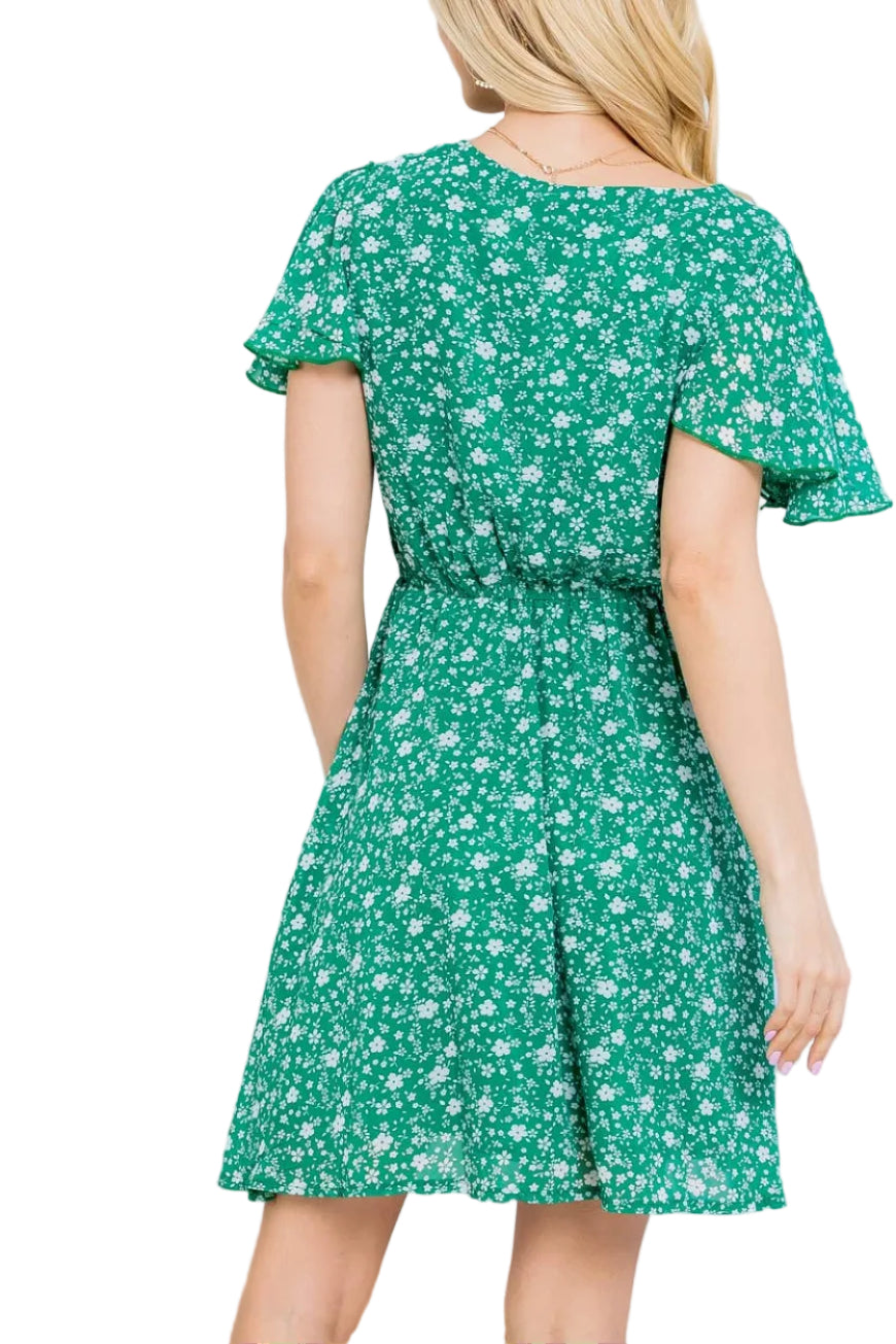 Woman wearing a green floral dress against a white curtain background