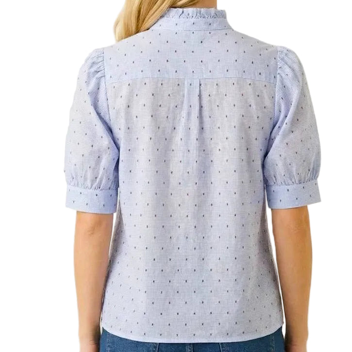 Woman wearing a light blue patterned shirt and denim shorts on a white background