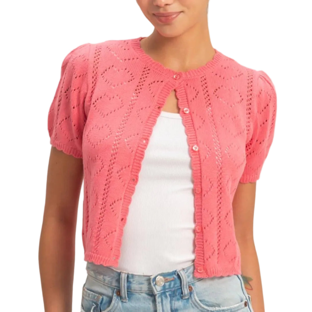 Woman wearing a pink knitted cardigan over a white shirt and blue jeans on a beige background