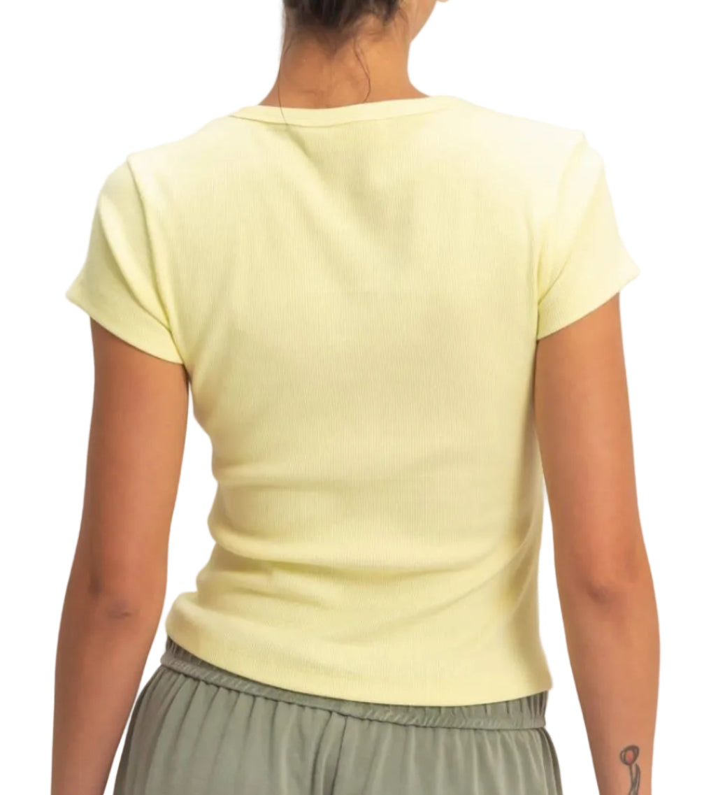 Person wearing a light yellow top and green pants against a plain background