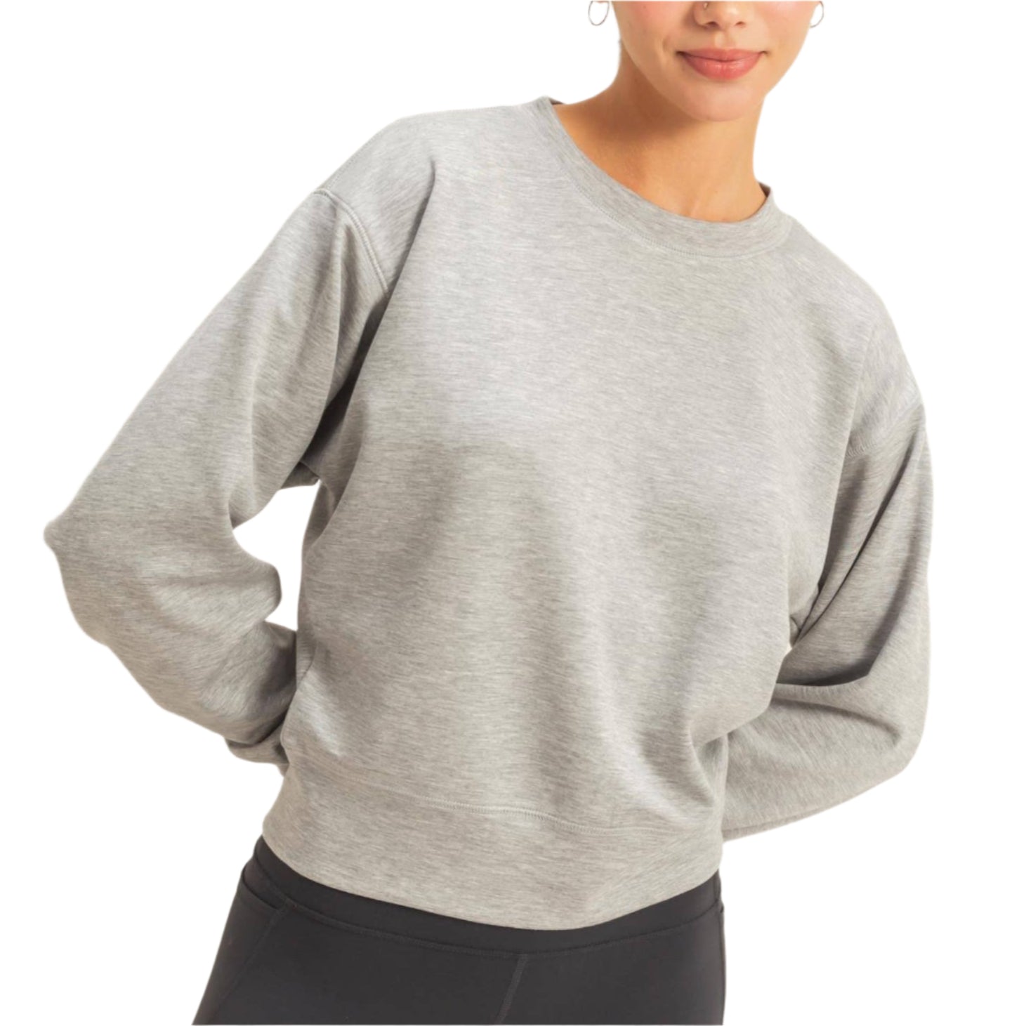 Woman wearing a gray sweater and black leggings against a plain background