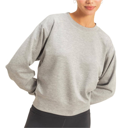 Woman wearing a gray sweater and black leggings against a plain background