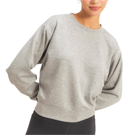 Woman wearing a gray sweater and black leggings against a plain background