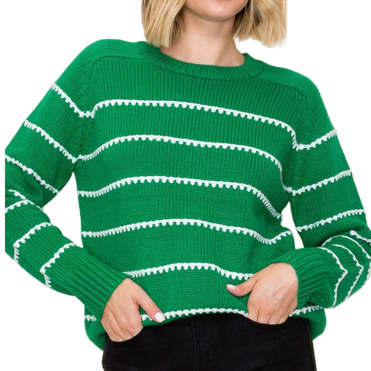 Woman wearing a green sweater with white stripes against a plain background