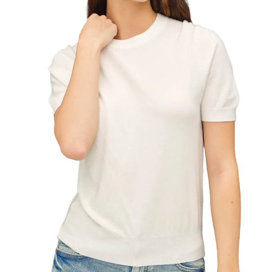 Woman wearing a white t-shirt and blue jeans against a black background
