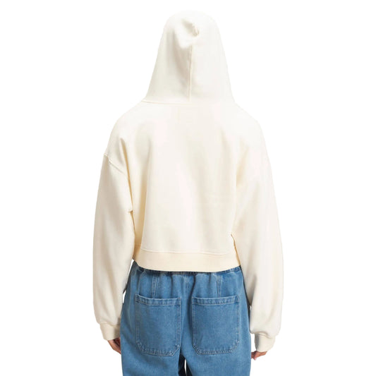 A person shown from the back wearing a cream-colored cropped hoodie and blue jeans against a plain light beige studio background.