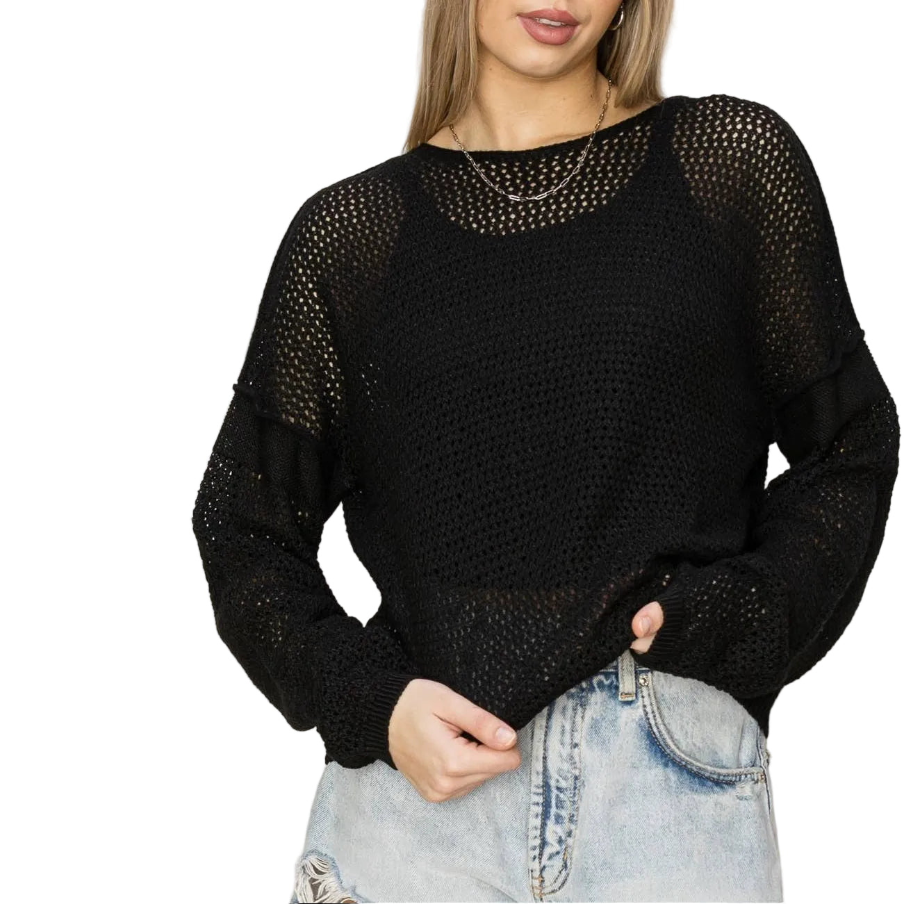 Woman wearing a black mesh sweater and light blue jeans against a plain background