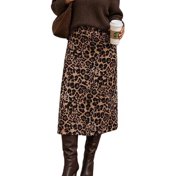 A woman stands outdoors wearing a brown ribbed off-the-shoulder sweater, a leopard-print midi skirt, and dark brown knee-high boots, while holding a coffee cup and carrying a shoulder bag.