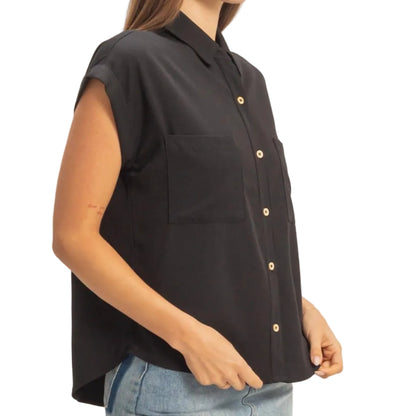 Woman wearing a black sleeveless shirt and denim skirt on a plain background