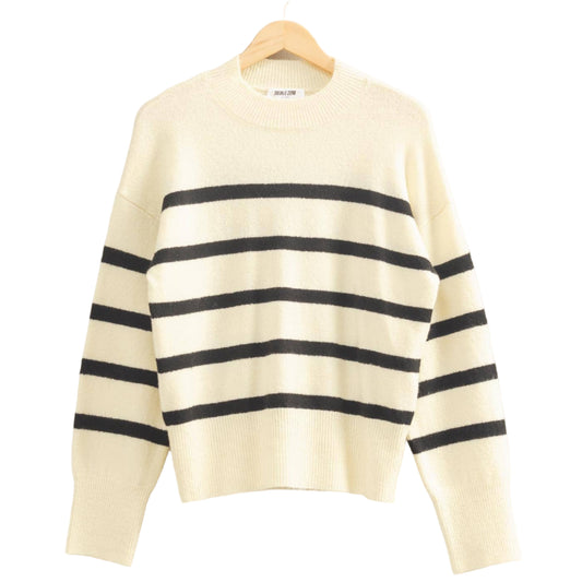 Cream-colored sweater with black stripes on a hanger against a light gray background