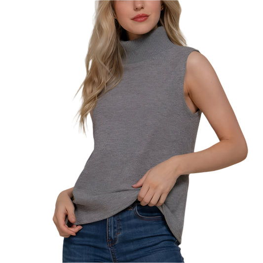 Woman wearing a gray sleeveless top and blue jeans against a beige background