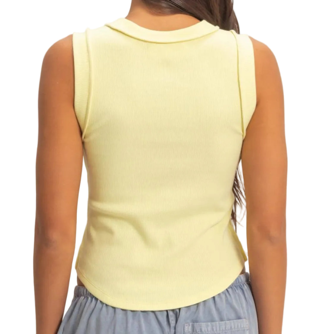 Person wearing a yellow sleeveless top and gray pants against a plain background